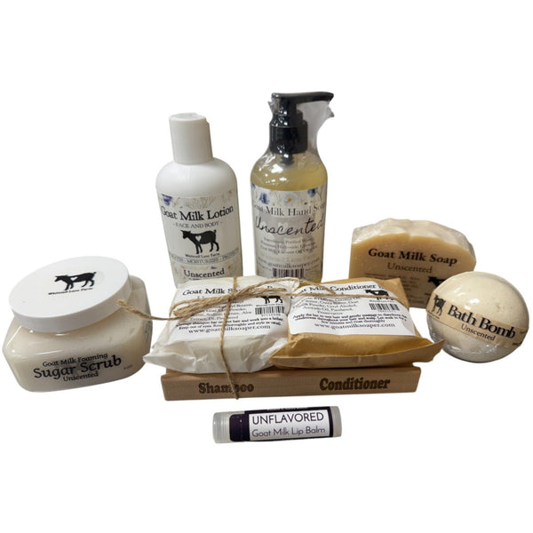 Collection of goat milk skincare products including lotion, soap, scrub, and bath bomb on a white background.