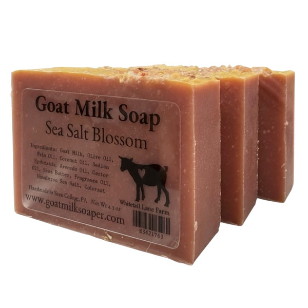 Three bars of goat milk soap with a label on a white background